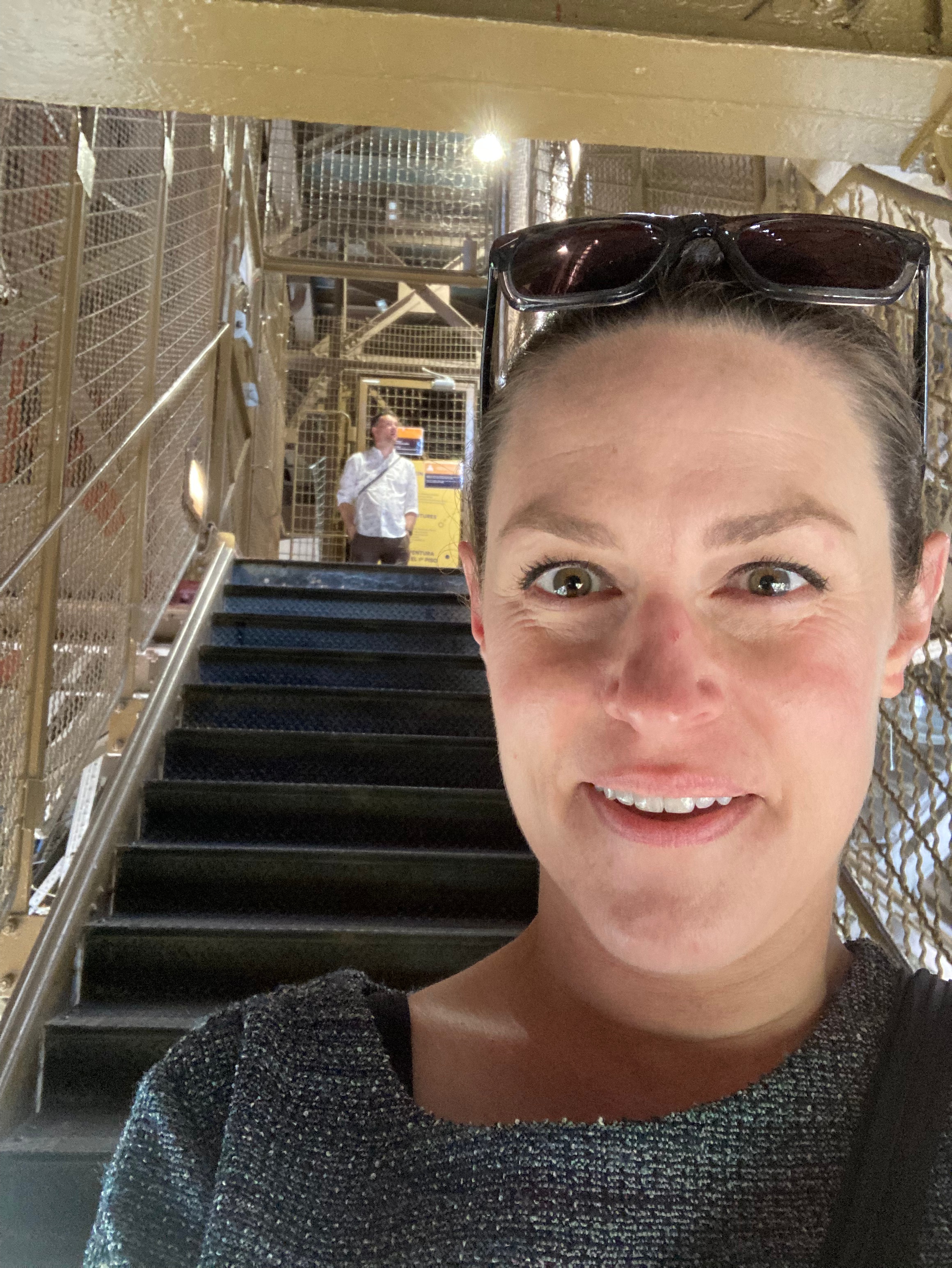 Staci (a light-skinned woman) standing in front of a staircase at the Eiffel Tower